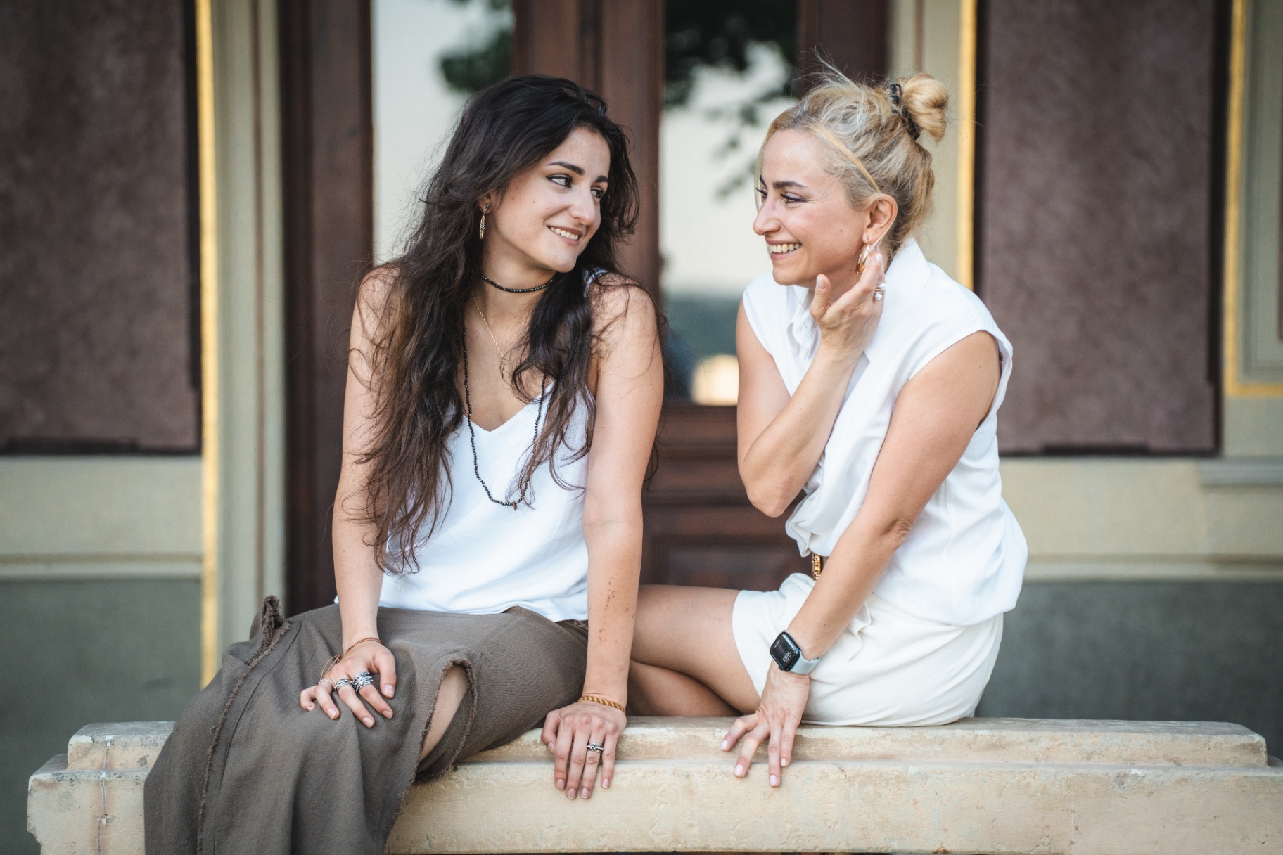 Mother and daughter laughing on a stone bench